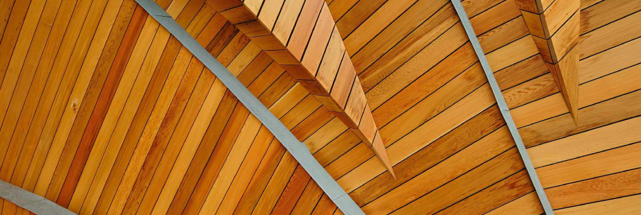 Cielo raso de listones de madera barnizada sostenido por vigas metálicas.